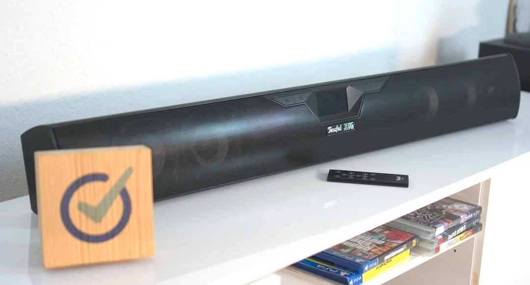 Eine Teufel Soundbar steht auf einem weißen Sideboard vor der Wand.